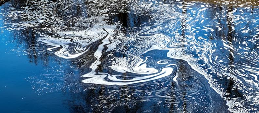 A photograph depicting a large slick of crude oil floating on the surface of a body of water.